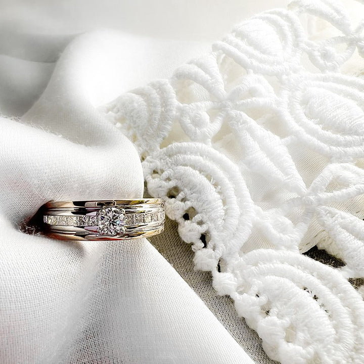 De Elegante damesring geelgouden band met briljant diamant 0.54ct van Excellent Jewelry schittert op witte, reliëf kantstof en straalt elegantie en romantiek uit.