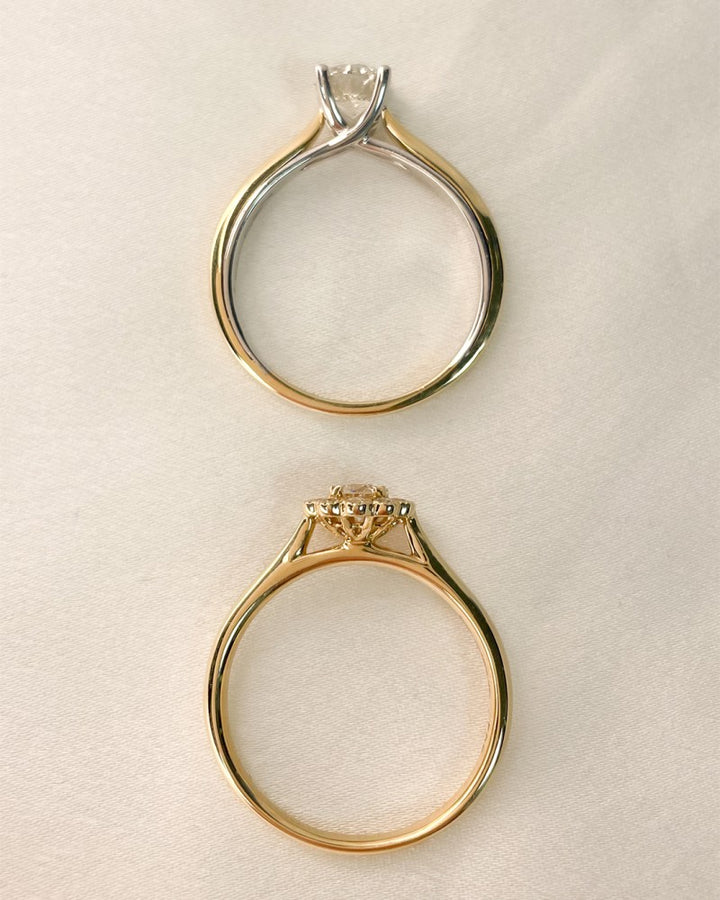 Twee 14k tweekleurige geel- en witgouden ringen van Excellent Jewelry, elk bezet met een 0,74ct H/SI-1 briljantdiamant, worden getoond op crèmekleurige stof - de ene van bovenaf gezien in een prongzetting, de andere van opzij gezien met elegante ontwerpdetails.