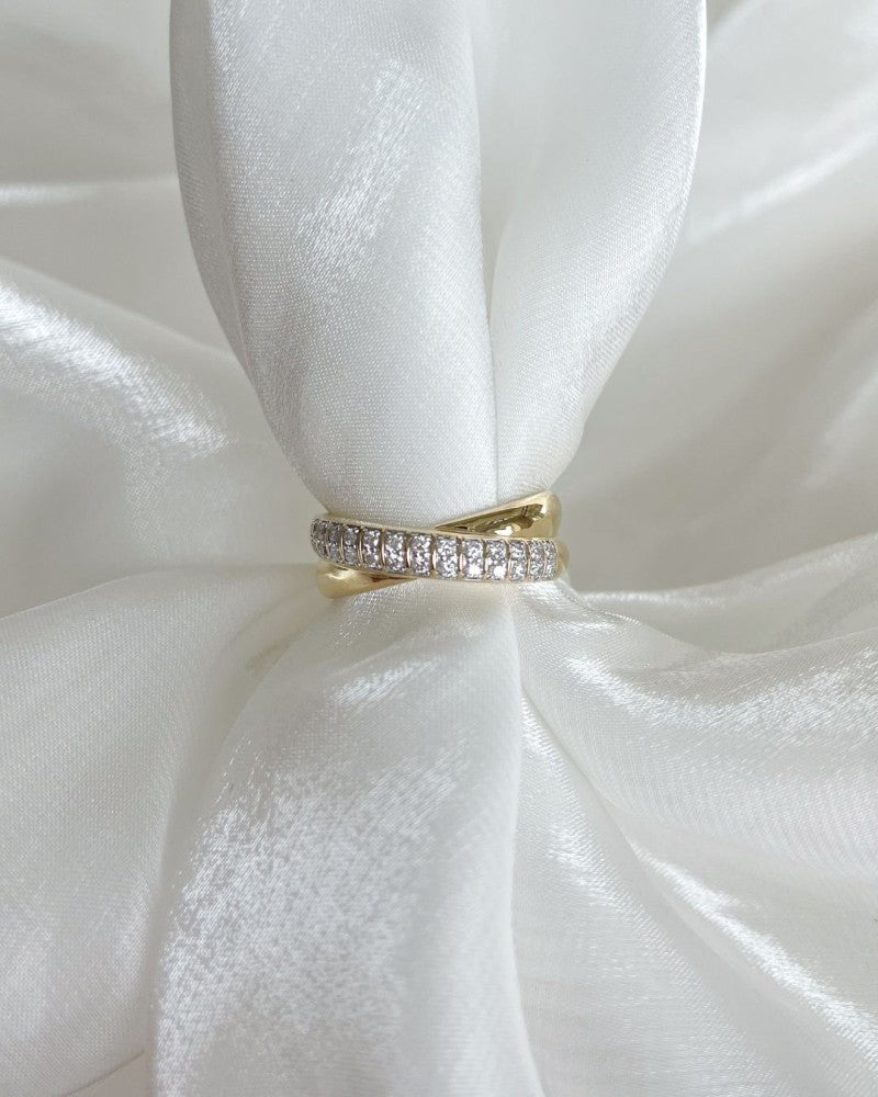 De Prachtige Geelgouden Ring met Gekruisde Banen en Pavégezette Briljanten 0.25 crt. van Excellent Jewelry schittert met twee overlappende banden, waarvan één elegant is bezet met briljantdiamanten.