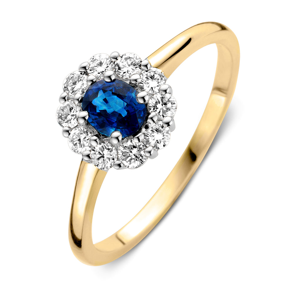 Bague en or jaune et blanc avec un saphir bleu central entouré de diamants brillants.