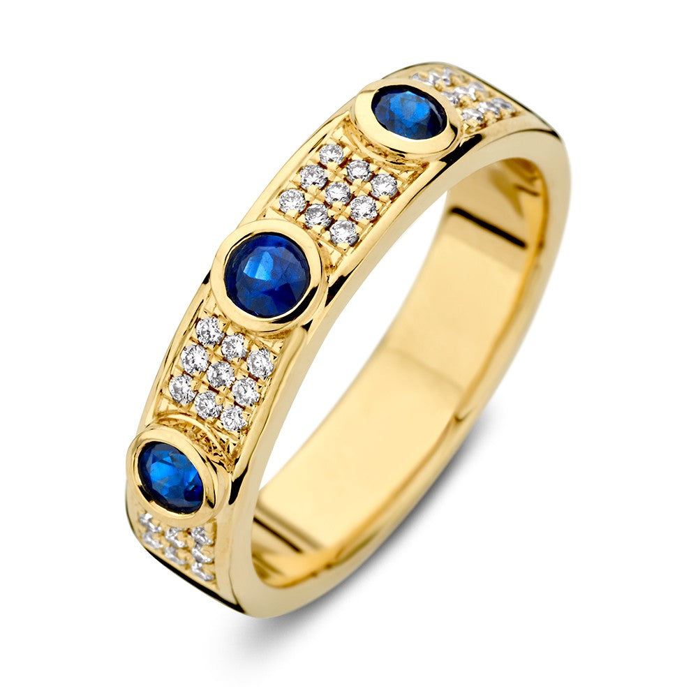 Bague en or jaune avec un diamant et trois saphirs bleus, ornée de petites pierres brillantes.