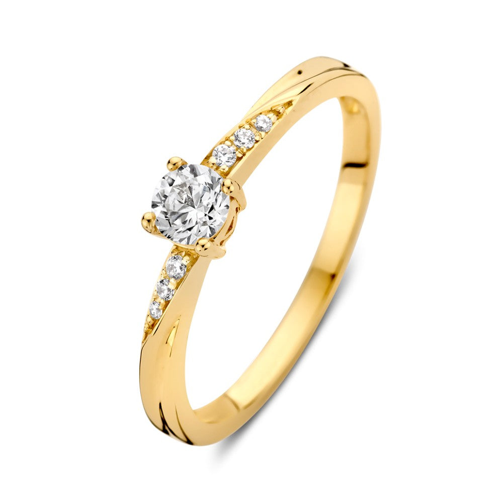 Bague en or jaune avec un zircon et un twist ludique, ornée de petites pierres brillantes.