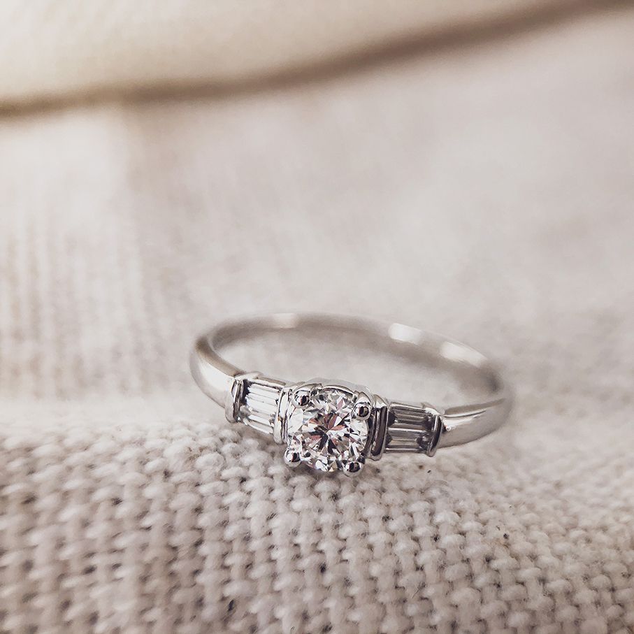 Bague en or blanc élégant avec centre en taille brillant et pierres latérales baguette