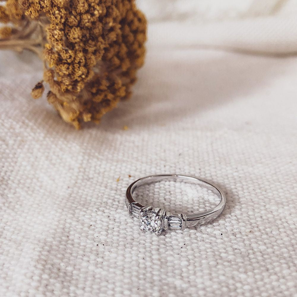 Bague en or blanc élégant avec centre en taille brillant et pierres latérales baguette