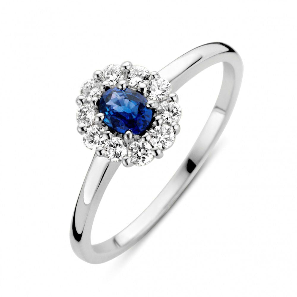 Bague en or blanc avec saphir bleu et diamants, ornée d'un saphir central entouré de diamants.