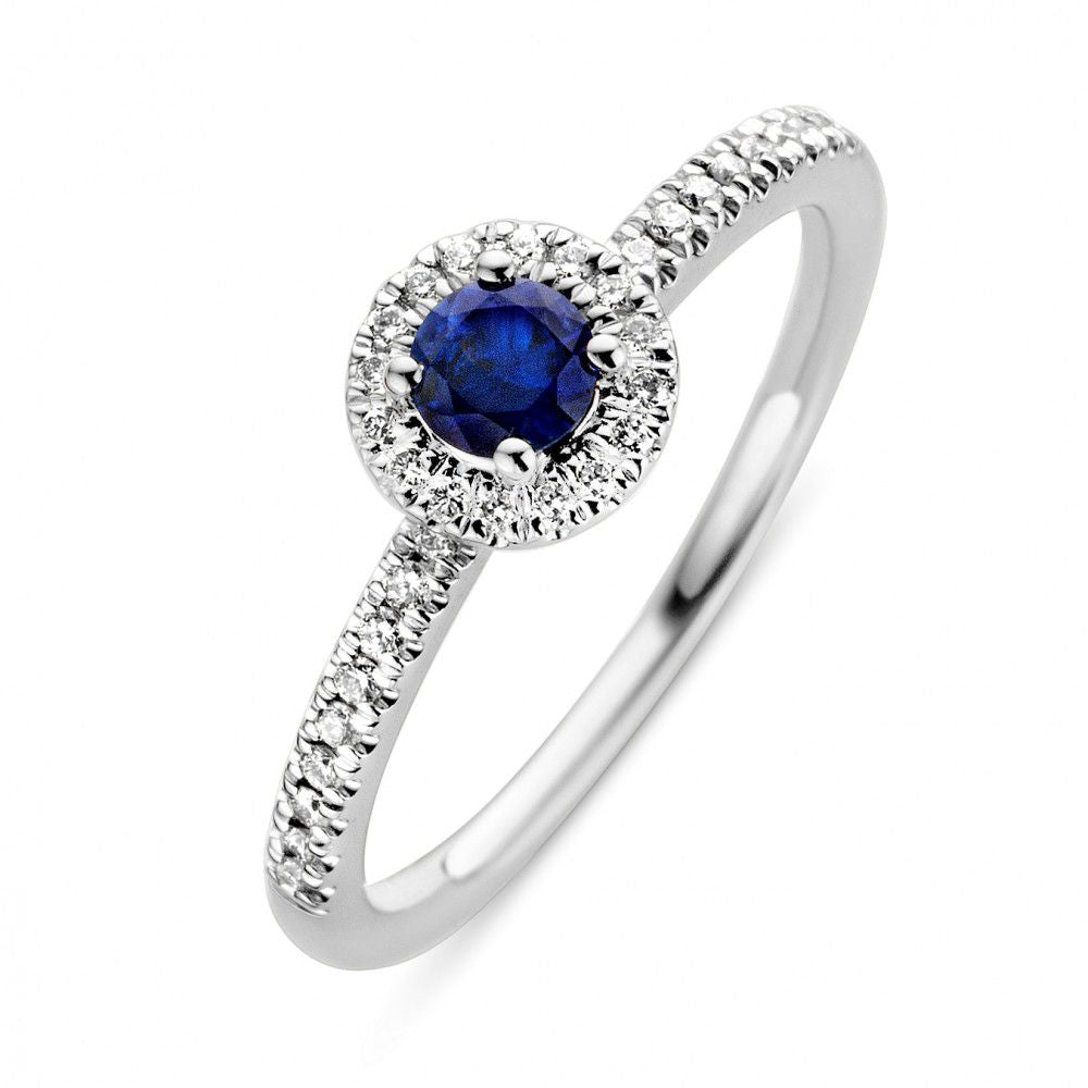 Bague en or blanc avec saphir bleu central entouré de diamants.