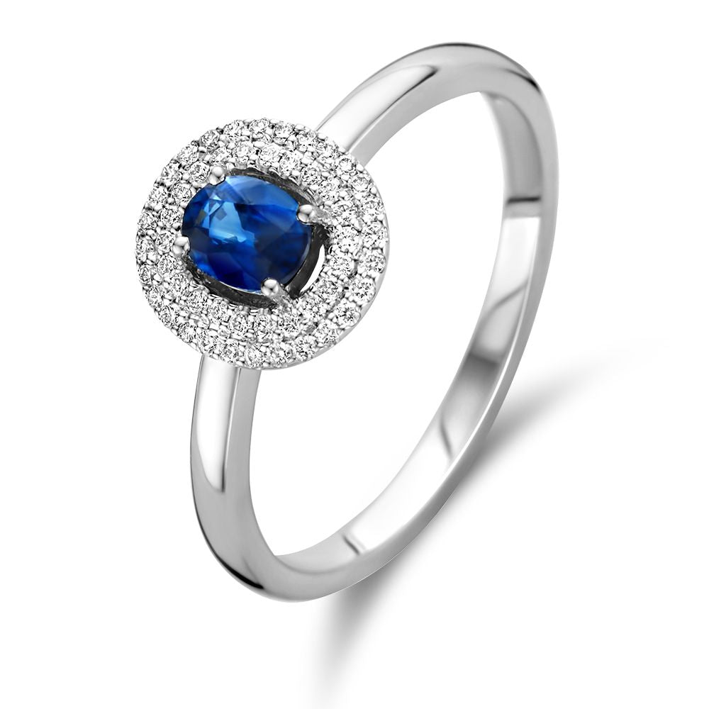 Bague en or blanc avec un saphir central et des diamants entourants.