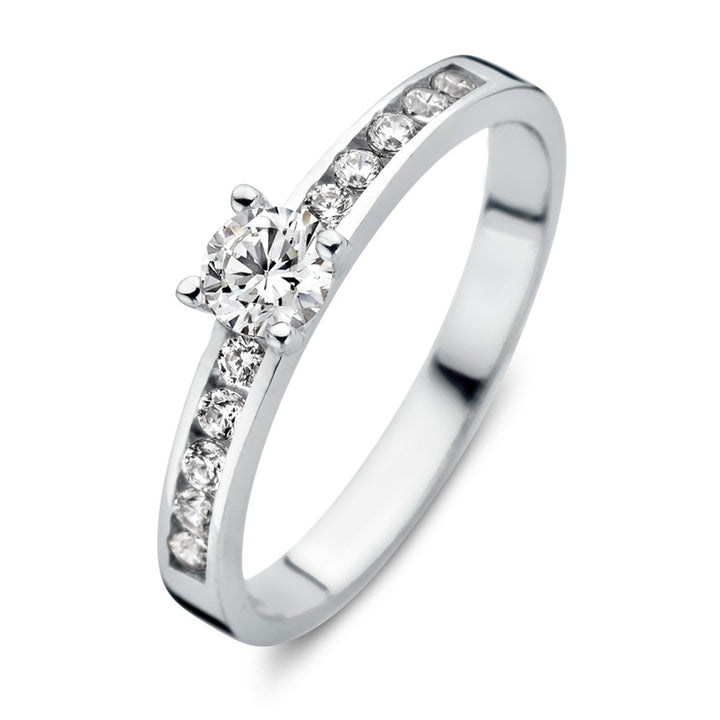 De Excellent Jewelry Witgouden Damesring met Zirkonia's - Subtiele Elegantie is een 14 karaat witgouden damesring met een centrale ronde zirkonia en kleinere zirkonia's langs de band, getoond op een witte achtergrond.
