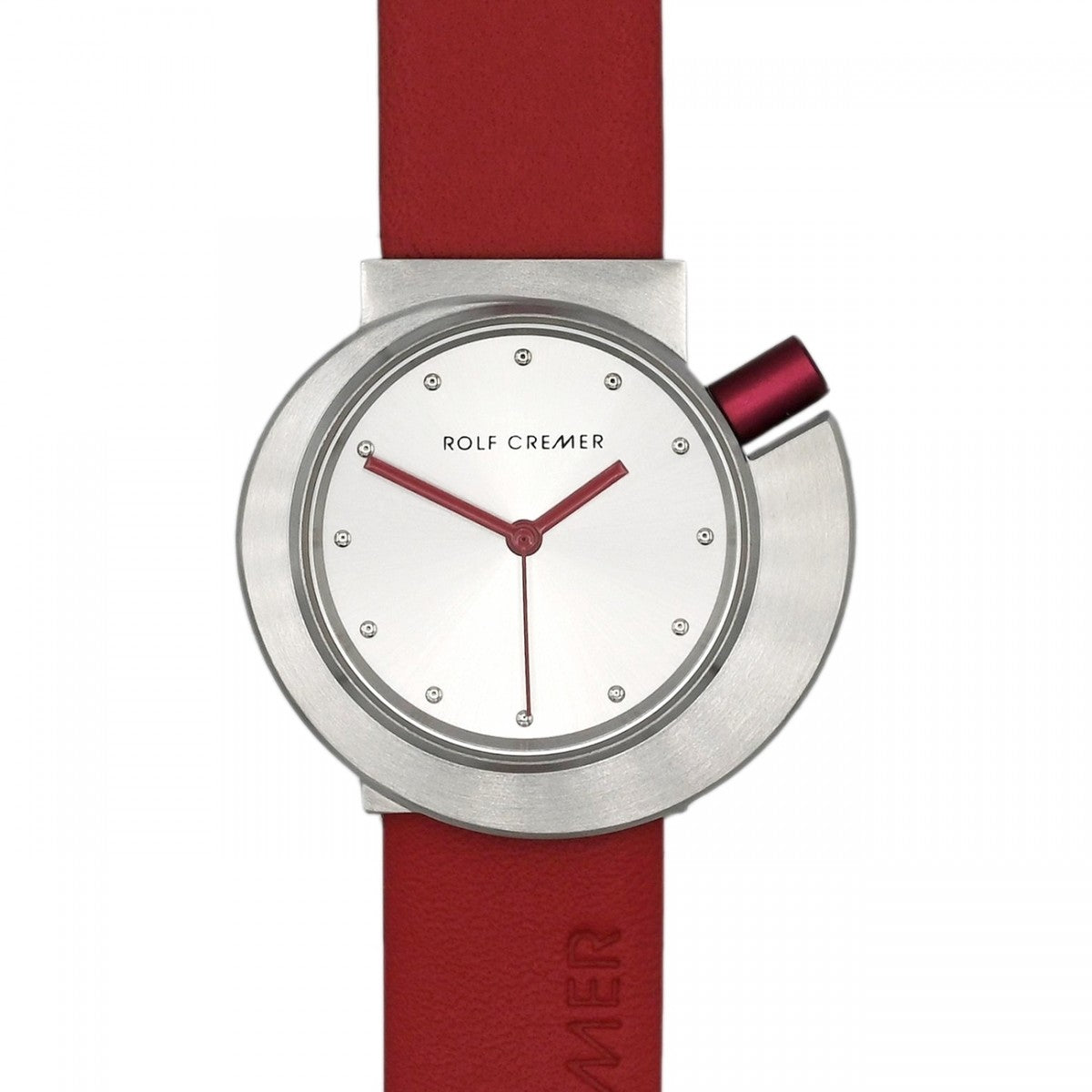 Montre Rolf Cremer avec un boîtier en acier inoxydable, cadran argenté et bracelet en cuir rouge.