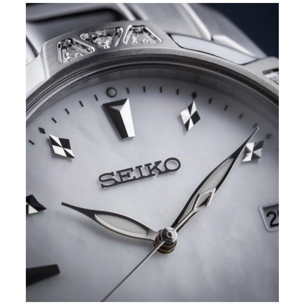 Close-up van een Seiko dameshorloge SKK727P1 met een witte parelmoer wijzerplaat, zilveren uurmarkeringen en wijzers, ruitvormige accenten en nauwkeurig Quartz uurwerk. De datumweergave is gedeeltelijk zichtbaar aan de rechterkant.