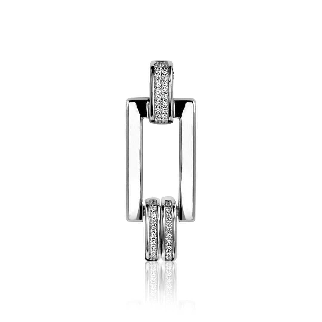 De Zinzi Hangers Zilver Mvh4 van Mart Visser bestaat uit een opvallende geometrische hanger van zilver met twee rechthoekige vormen die met elkaar verbonden zijn door ronde banden, versierd met glinsterende steentjes. De hanger straalt een moderne en elegante esthetiek uit op een subtiel gearceerde witte achtergrond.