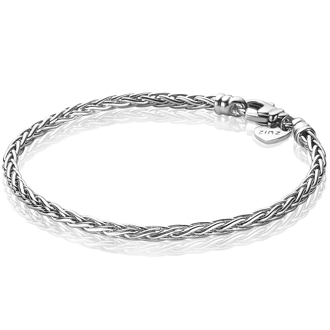 De Zinzi Armband Zilver Zia1912, een zilveren touwkettingarmband met een karabijnsluiting, rust op een reflecterend oppervlak. Het ingewikkelde weefpatroon is een voorbeeld van elegant design, wat Zinzis vakmanschap weerspiegelt. Met een lengte van 18 inch voegt dit tijdloze stuk verfijning toe aan elk ensemble.