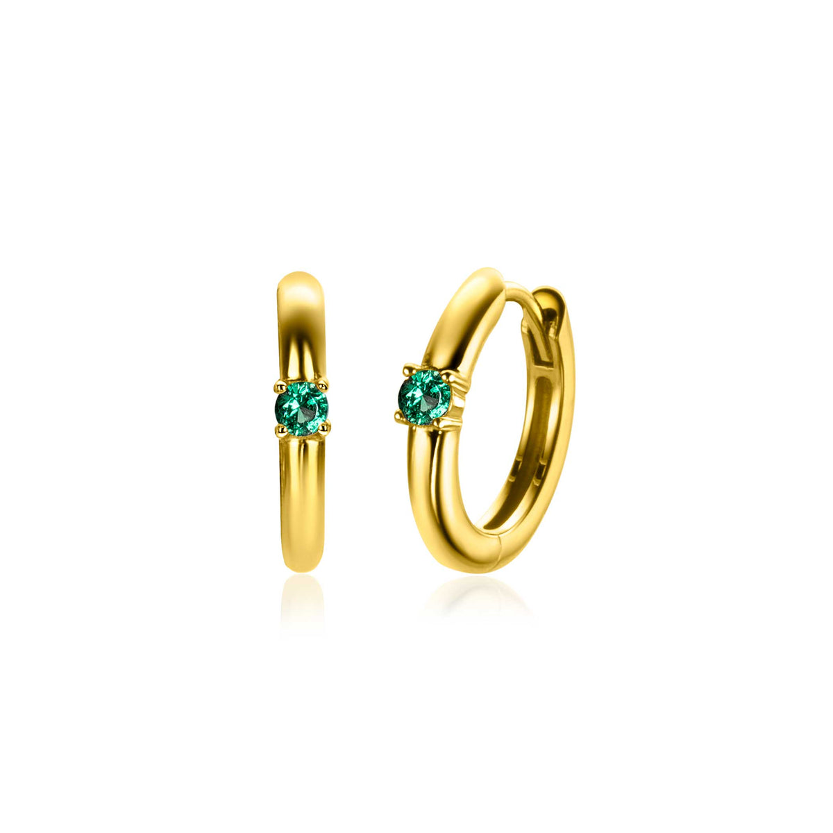 Boucles d'oreilles dorées avec un cristal vert en son centre.
